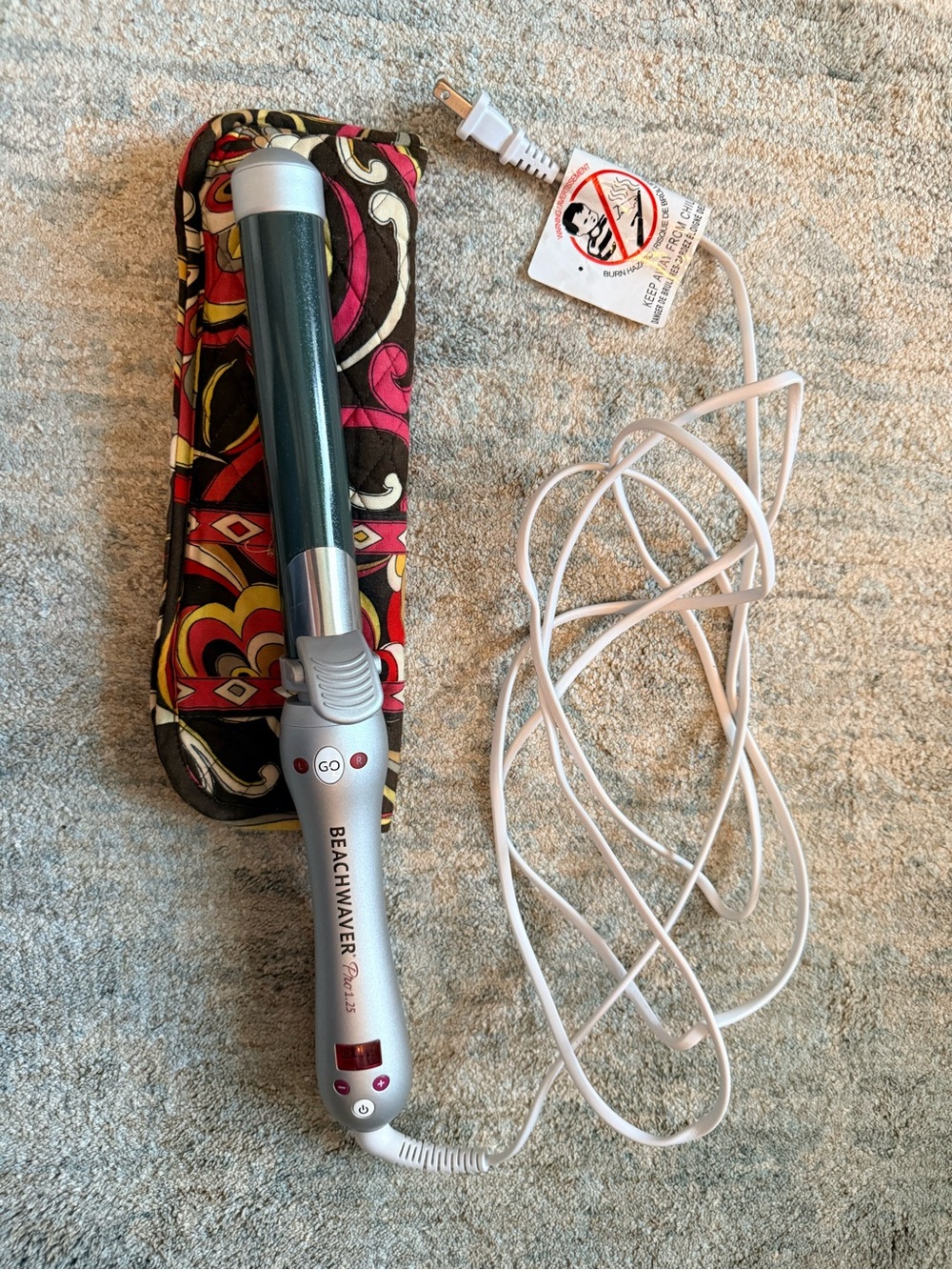 The Beachwaver Co. curling wand in teal and silver with patterned heat sleeve